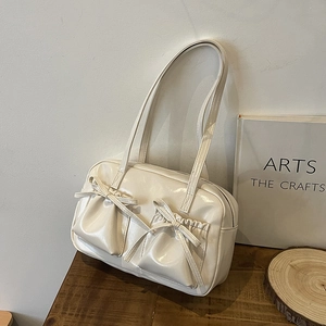 Détail du sac cabas crème brillant avec nœuds décoratifs et poches frontales doubles