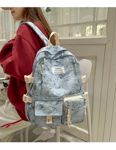 Detail of light blue tie-dye backpack showing spacious side pockets and sturdy woven straps
