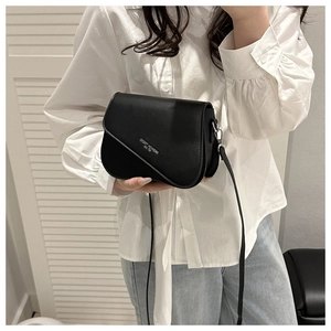 Detail of black leather crossbody bag featuring white printed text and metal buckle