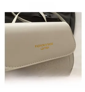 Detailed macro view of the houndstooth pattern and gold lettering on this beige crossbody bag