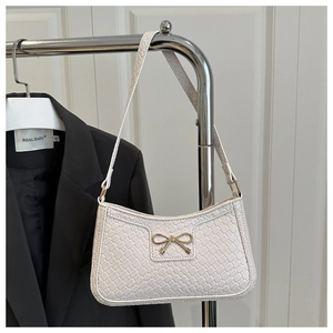 Détail du sac blanc à texture tressée avec boucle nœud doré et bandoulière élégante