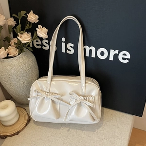 Détail du sac en cuir verni crème avec poches à cordon et nœuds élégants au fini brillant