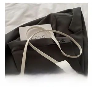 Detail of white leather shoulder bag with gold 'FASHION & BAGS' text on brown blazer