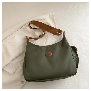 Detail of dark green nylon crossbody bag with brown FASHION leather patch and strap