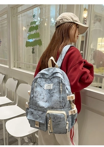 Detail of marble pattern backpack featuring ivory straps and side buckles on a blue-grey base