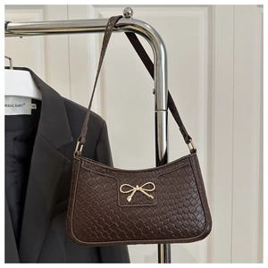 Détail de la texture cuir tressé et boucle nœud dorée sur un sac à bandoulière chocolat