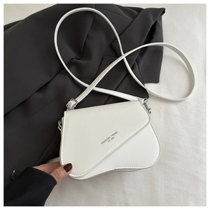 Detail of asymmetric flap on white PU leather bag with Fashion Trend EST 1996 text