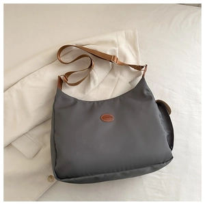 Detailed view of dark gray nylon shoulder bag with brown leather FASHION patch