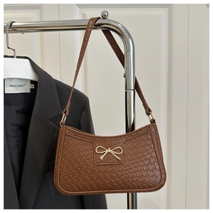 Détail de la texture tissée du sac marron avec un fermoir nœud en métal doré