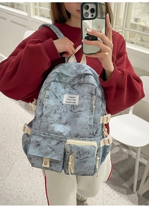 Detail of large marble print backpack featuring functional straps and multi-pocket design