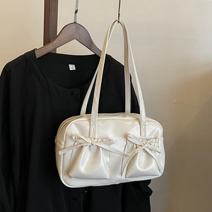 Détail d'un sac à bandoulière crème avec deux poches avant et nœuds décoratifs
