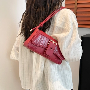 Elegant red crocodile texture shoulder bag with gold buckle displayed on a model