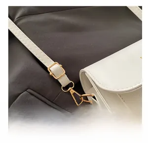 Detail shot of the adjustable golden buckle and hardware on a white leather shoulder strap