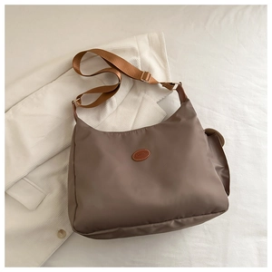 Detail view of coffee brown nylon crossbody bag featuring the FASHION leather patch