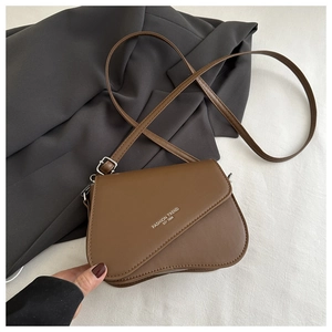 Detail of brown shoulder bag showing curved flap design and Fashion Trend Est 1996 logo
