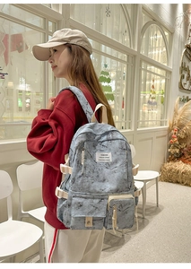 Detail of grey marble canvas backpack with multi-pocket structure and cream webbing handles