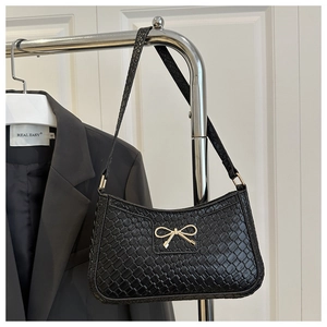 Détail du sac bandoulière noir texture tissée avec fermoir nœud doré élégant