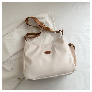 Detail showing the adjustable wide brown shoulder strap and fashion leather patch on bag