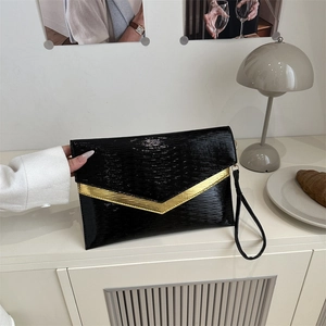 Chic black glossy envelope clutch with gold V-detail and wristlet strap for party events