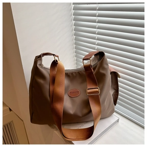 Detail of tan crossbody bag showing wide adjustable strap and golden metal buckles