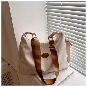 Detail of beige nylon crossbody bag with brown wide strap and leather fashion logo label