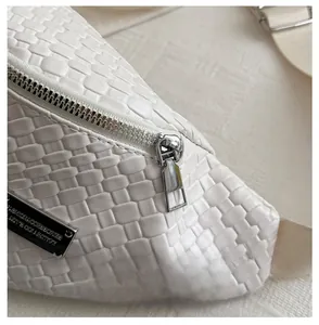 Detail of white woven leather crossbody bag with silver zipper and fashion label