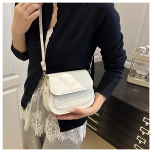 Detail of white leather crossbody bag showing the golden embossing and geometric texture