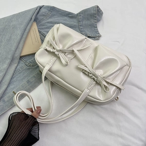 Détail du sac fourre-tout crème avec nœuds décoratifs et texture plissée élégante