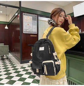 Student backpack detail showing large capacity black canvas with white buckle straps and side pocket