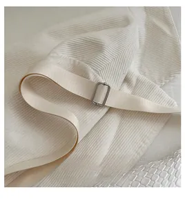 Detail of adjustable woven strap with silver metal buckle on a beige ribbed chest bag