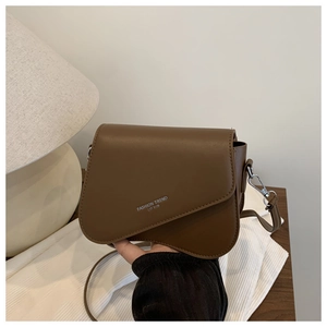 Detail of dark brown matte PU leather shoulder bag with asymmetrical flap and silver text