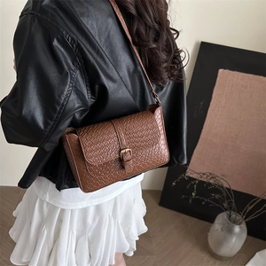 Brown woven leather shoulder bag with vintage gold buckle shown in a lifestyle setting