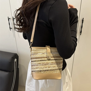 Fashionable woven straw bucket bag with beige leather trim and crossbody strap design