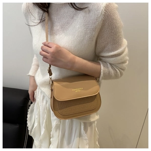 Detail of camel saddle crossbody bag featuring embossed texture and gold lettering