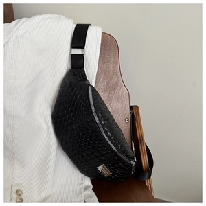 Detail of black woven chest bag with silver zipper and adjustable strap on a white jacket