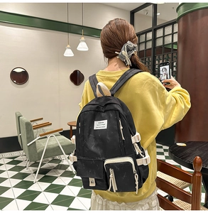 Close-up of black multi-pocket canvas backpack featuring white fashion label for students