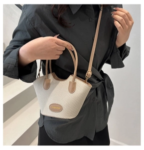 Detail der beigen geflochtenen Eimertasche mit braunem Kunstleder und Modeplakette