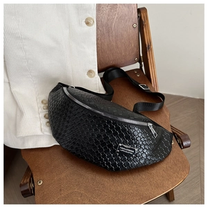Detail of black woven chest bag texture with silver metal plaque on a wooden chair