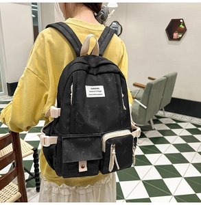 Detail of the black nylon backpack showing multi-pocket structure and buckle straps