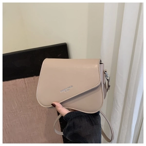 Detail of beige saddle bag showing silver 'FASHION TREND' logo and leather strap