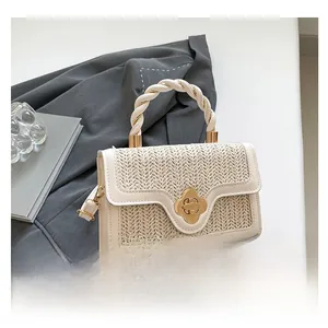 Detailed view of beige straw woven bag with leather handle and gold floral twist lock
