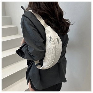 Detail of white woven chest bag featuring silver metal zipper and adjustable strap