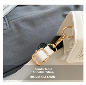 Detail of adjustable strap with gold buckle and woven texture on a white shoulder bag