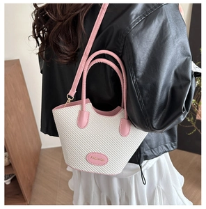 Détail du sac seau tissé avec garniture en cuir rose et bandoulière réglable pratique