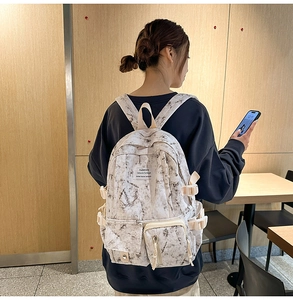 Detail of white marble print backpack featuring multiple pockets and side buckle straps