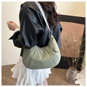 Détail du sac demi-lune en nylon vert clair plissé avec large bandoulière grise