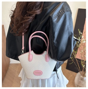Detailansicht der gewebten Beuteltasche in Weiß und Rosa, getragen von einem Modell in Leder