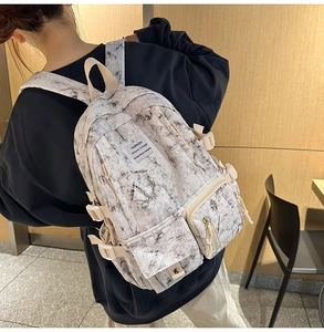 Detail view of large marble print backpack featuring side adjustable straps on model