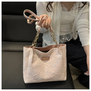 Detail of pink embroidered tote bag with gold chain strap and textured fabric