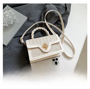 Detail of off-white woven handbag with rope handle and gold clover-shaped metal clasp